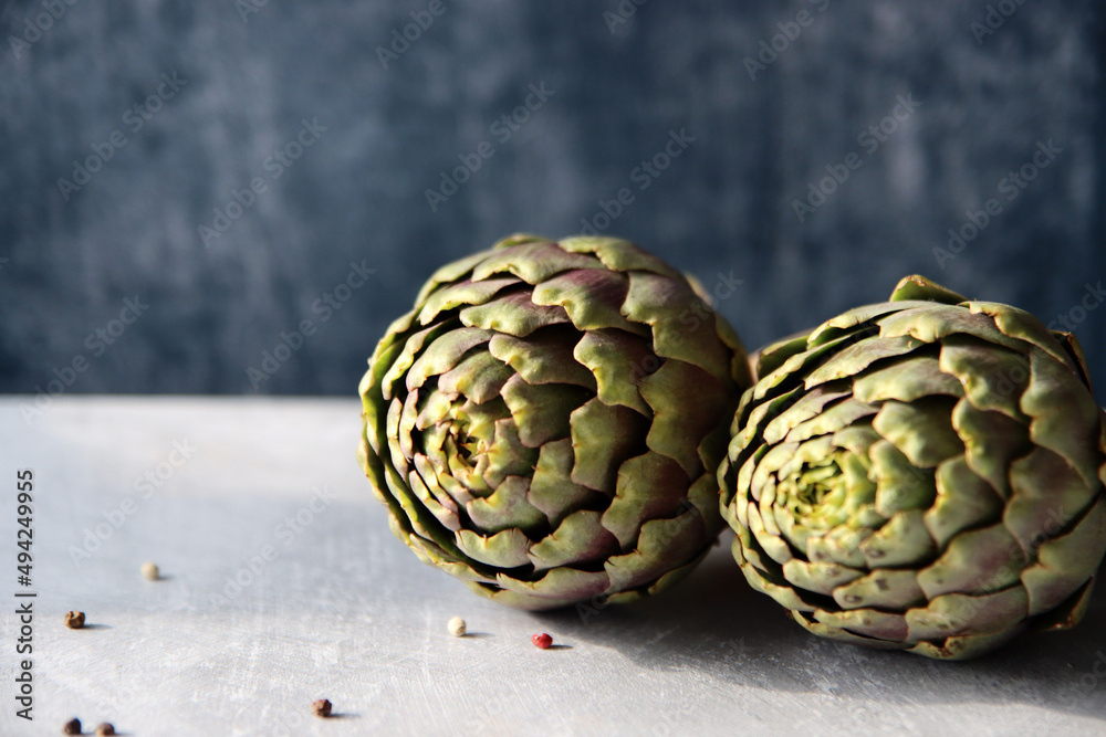 Fototapeta premium Still life with fresh artichoke flowers. Close up photo of beautiful natural pattern. Eating healthy concept. 