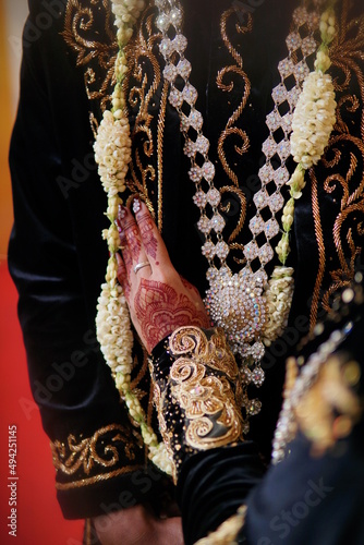 Bride's hand with henna painting for wedding ceremony. Beautiful Javanese bride Showcasing her dress and jewelery and her boyfriend's designs. Henna Maroon