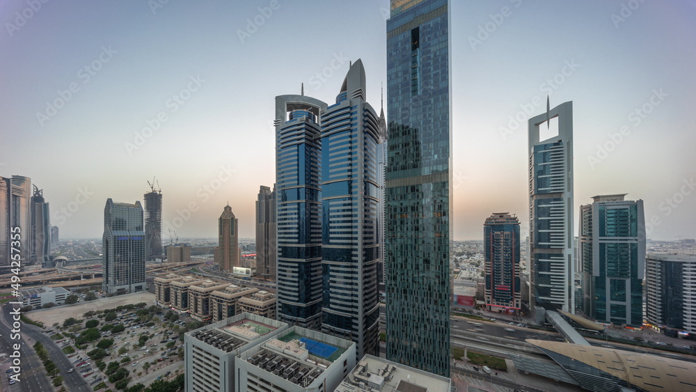 Obraz premium Aerial view of Dubai International Financial District with many skyscrapers day to night timelapse.