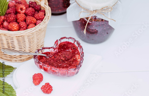 Homemade healthy jam with raspberries on a white wooden table. Treatment of colds. Conservation and summer harvesting.