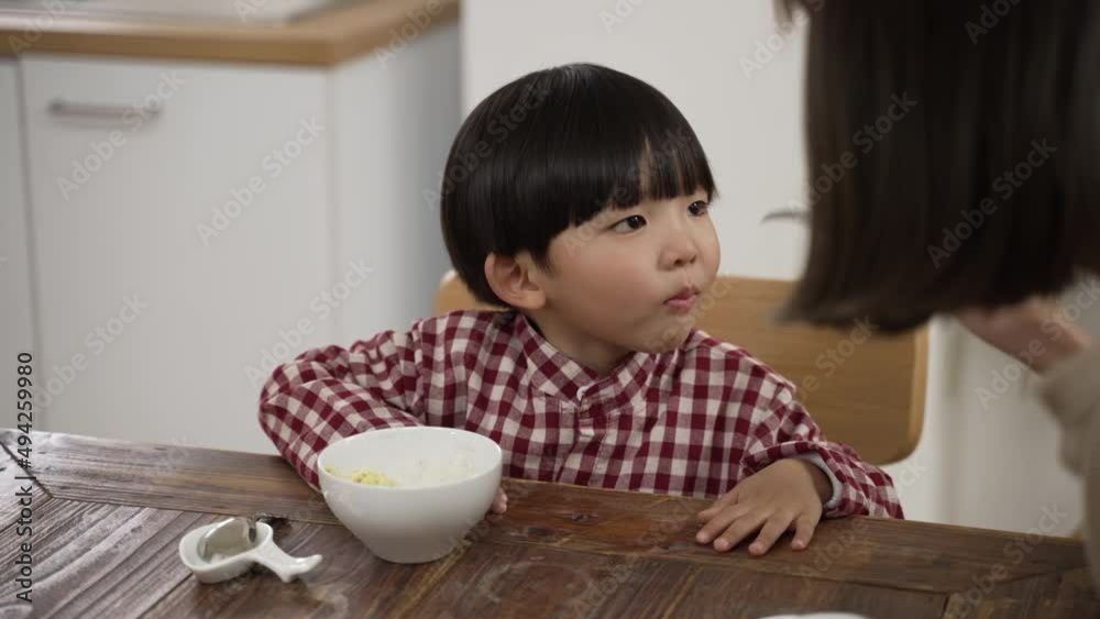slow motion with closeup of a lovely Japanese preschool boy saying yummy as his mom puts a piece of food in his mouth at dinner table at home slow motion with closeup of a lovely Japanese preschool boy saying yummy as his mom puts a piece of food in his mouth at dinner table at home