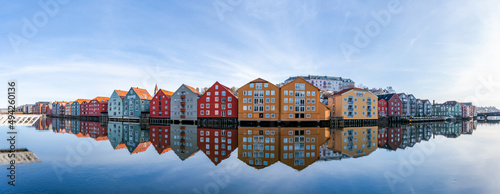 Wide panoramic view of old colorful wooden houses with reflections in river Nidelva in the Brygge district in Trondheim, Norway photo
