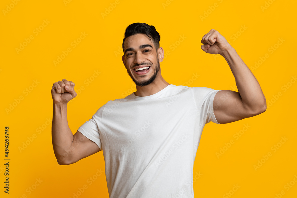 Fototapeta premium Cheerful athletic middle eastern man showing his muscles