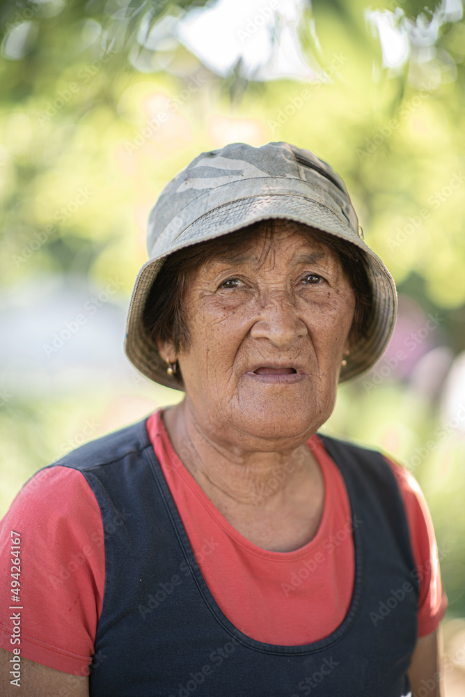 Close-up portrait of a pensive elderly woman in a panama hat in a summer garden.