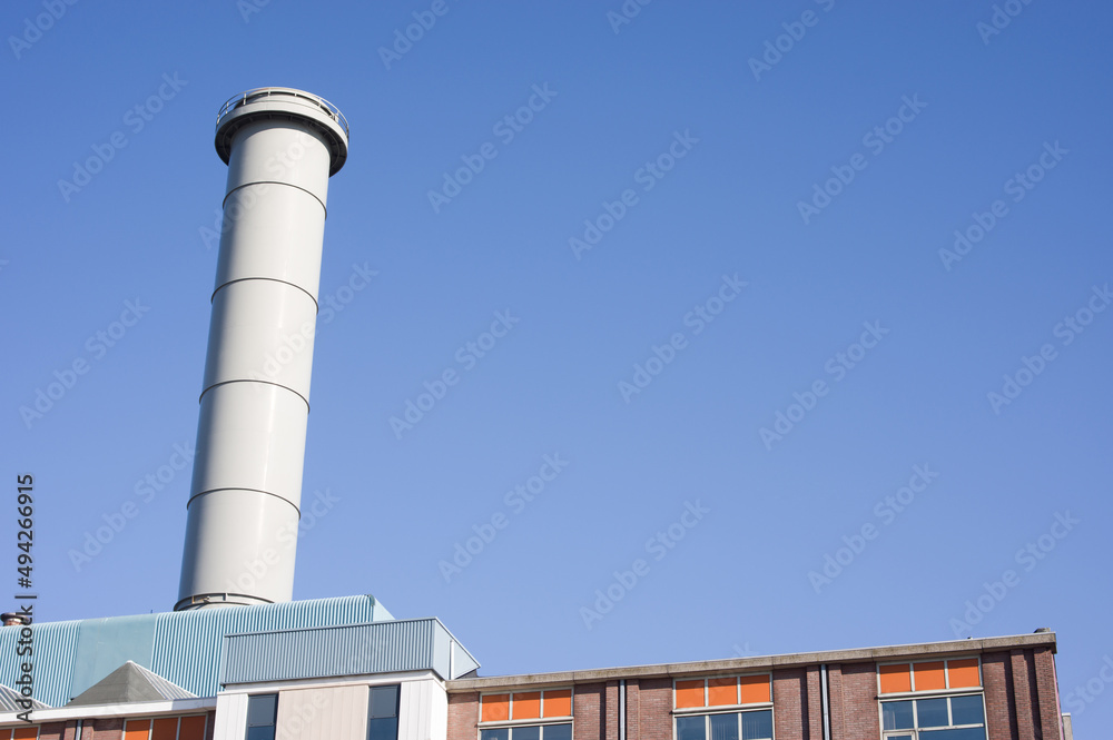 Top of a factory with industrial chimney with a clear blue sky in the Netherlands Top of a factory with industrial chimney with a clear blue sky in the Netherlands