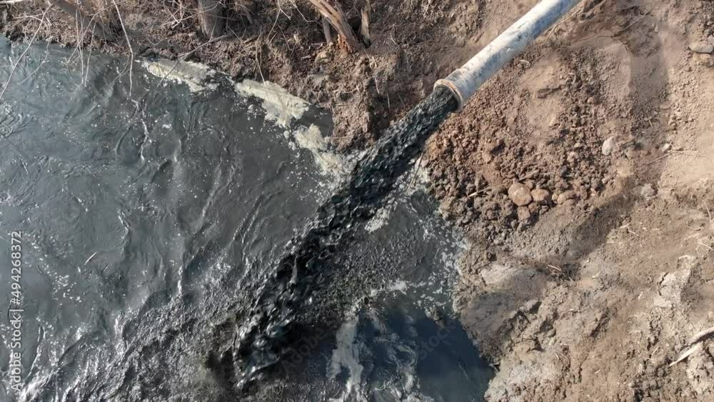 Dirty water flows from the pipe. Aquatic pollution. Ecological catastrophe. The black liquid flows into the river. Dirty water flows from the pipe. Aquatic pollution. Ecological catastrophe. The black liquid flows into the river.