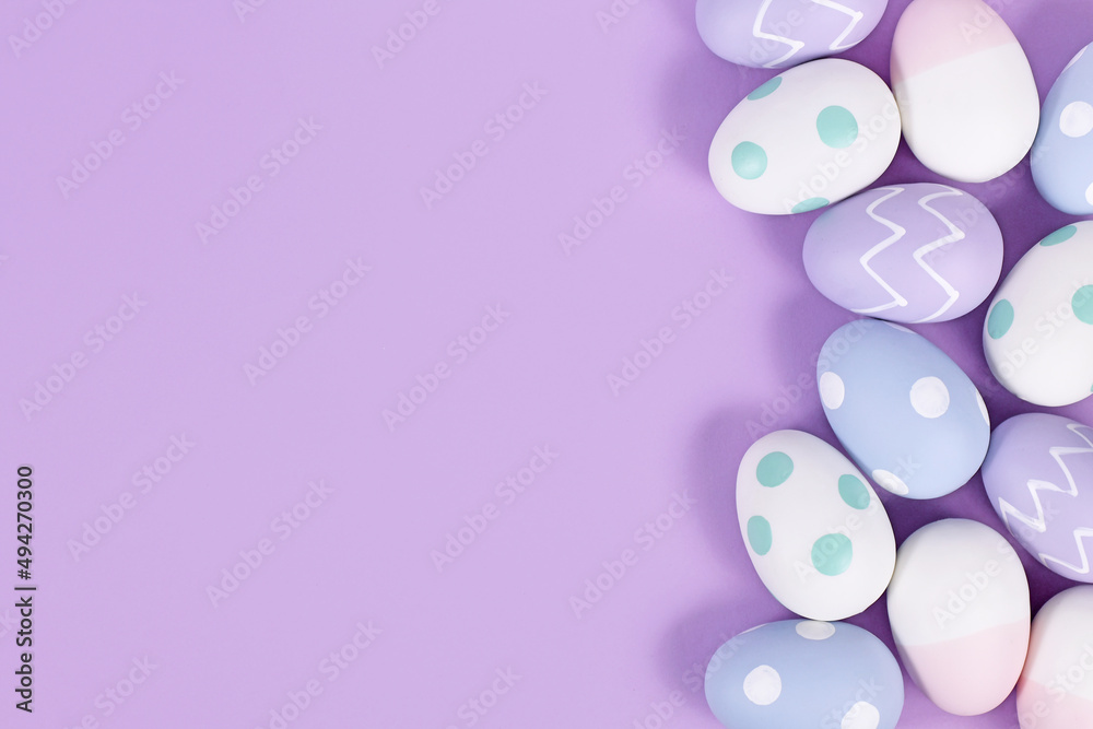 Pastel colored painted easter eggs on side of violet background with copy space Pastel colored painted easter eggs on side of violet background with copy space