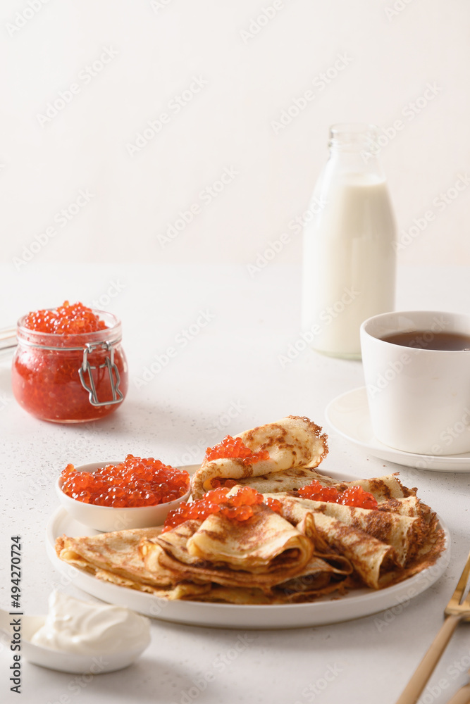 Russian thin pancakes or blini with red caviar on white background. Close up. Vertical format. Russian thin pancakes or blini with red caviar on white background. Close up. Vertical format.