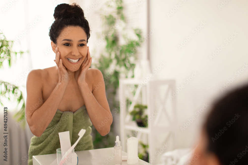 Happy young brunette woman touching smooth silky skin on her face after bath at home, copy space Happy young brunette woman touching smooth silky skin on her face after bath at home, copy space