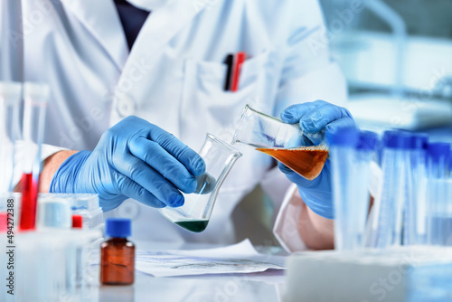 Researcher working whit fluids in flasks in the chemical laboratory. Scientist mixing chemical liquids in the chemistry lab