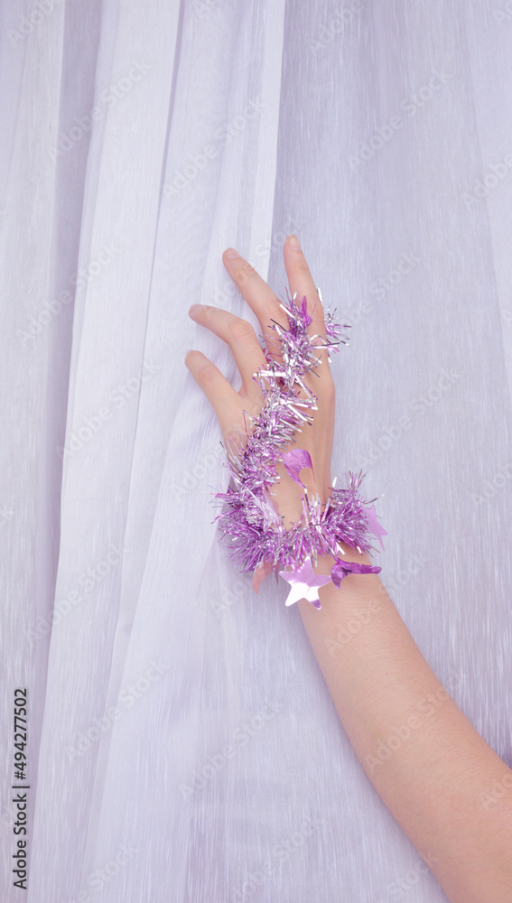 Woman hand with purple party glitter string in white voile background