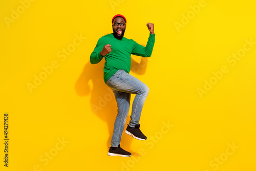 Photo of glad successful man celebrate victory wear specs red beanie green shirt isolated yellow color background