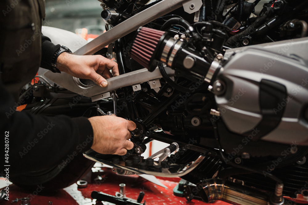 Repairman repair motorcycle, maintenance in garage. Mechanic fixing bike in a modern shop