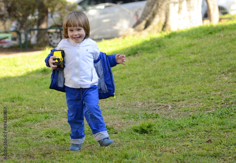 Cute little boy is running on the playground. The child plays with the car and laughs. positive baby Cute little boy is running on the playground. The child plays with the car and laughs. positive baby