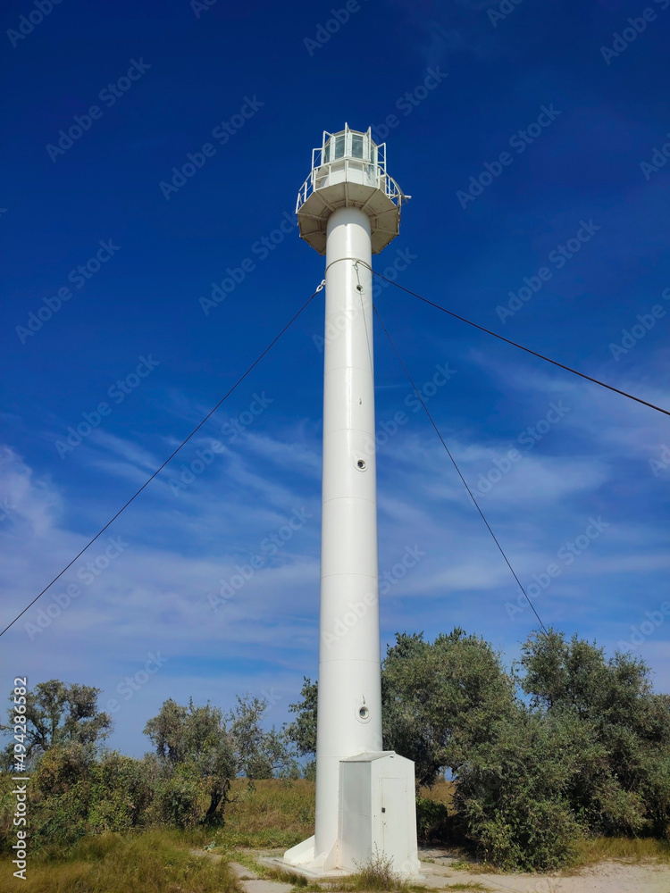 old lighthouse against a bright blue sky with clouds