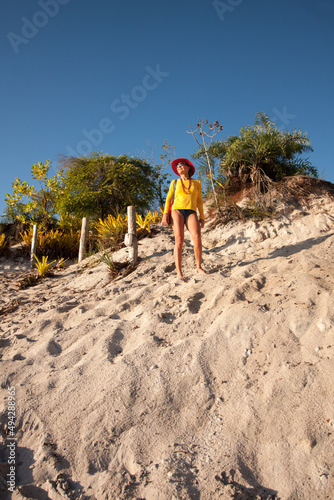Lady standing at the top of a sand dune at the river beach called Prianha in Caraiva, Bahia, Brazil
