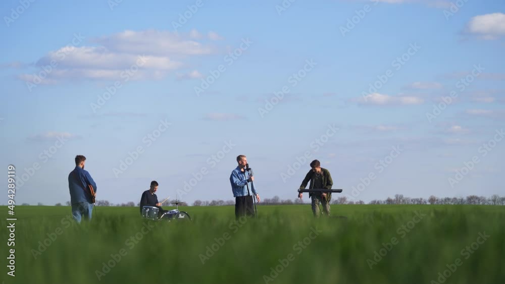 Emotional and active performance of a boys band in the green fields. Music band playing music and sing while drone flying around them. Emotional and active performance of a boys band in the green fields. Music band playing music and sing while drone flying around them.