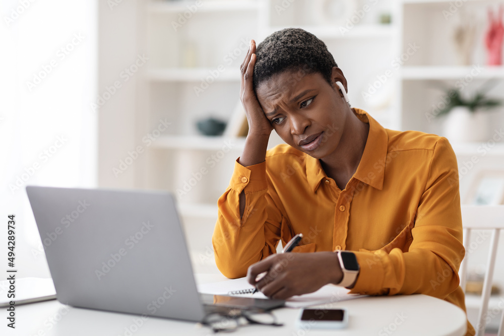Bored black lady attending webinar, sitting in front of laptop Bored black lady attending webinar, sitting in front of laptop