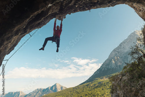 rock climber climbs a difficult route on a rock in the form of an arch