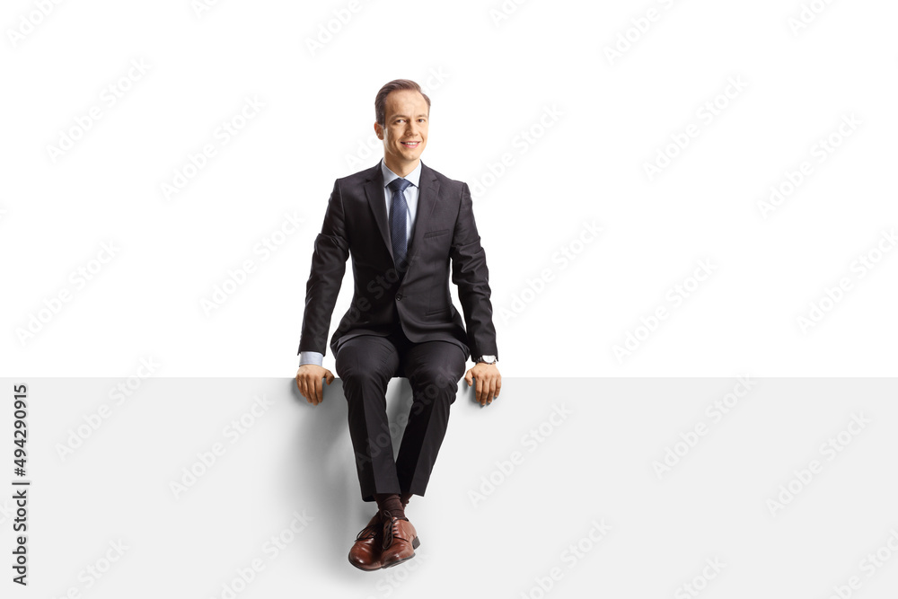 Professional man in suit and tie sitting on a blank panel Professional man in suit and tie sitting on a blank panel