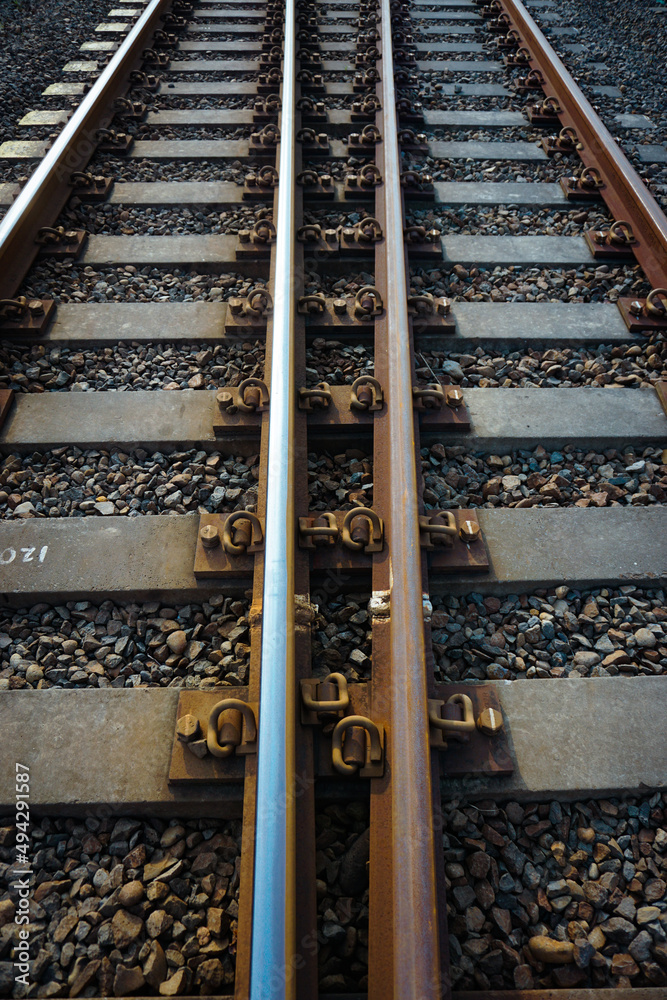 Naklejka premium The railroad tracks passed through the yellow grooved bearings buried under small shards of rock.