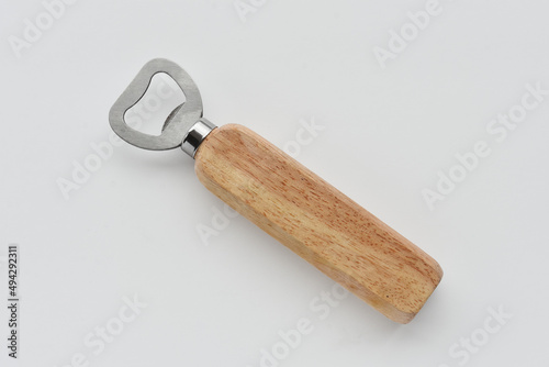 A top view image of a wooden handled bottle opener on a light grey background.  photo