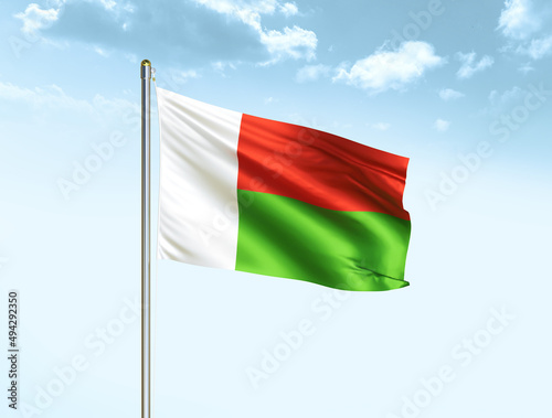 Madagascar national flag waving in blue sky with clouds. Madagascar flag. 3D illustration