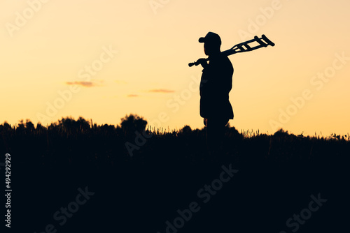 silhouette of a man holding crutches on his shoulder, liberation from illness and crutches