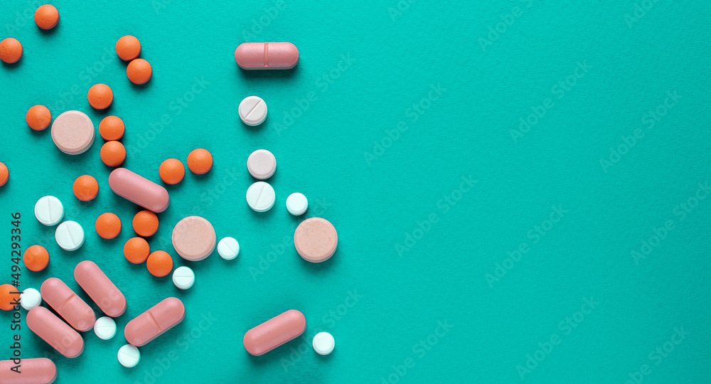 A lot of tablets on a turquoise background . probiotic capsule and antibiotic tablet