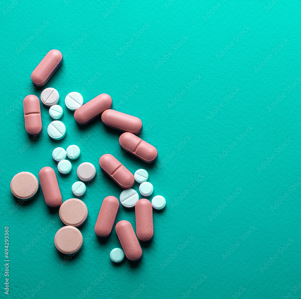 A lot of tablets on a turquoise background . probiotic capsule and antibiotic tablet A lot of tablets on a turquoise background . probiotic capsule and antibiotic tablet