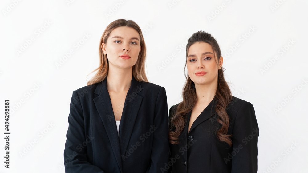 Concept of partnership in business. Two Young businesswoman dressed black formal suit standing studio isolated white background.