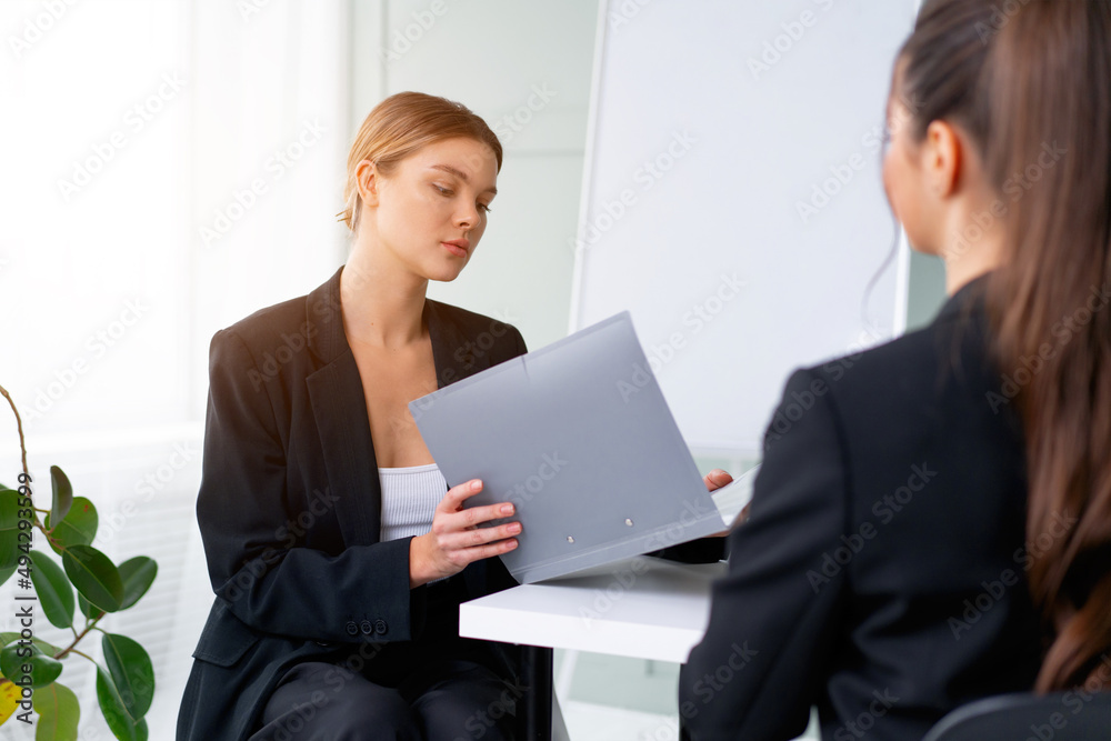 Job interview. Business, career and placement concept. Young blonde woman holding resume, while sitting in front of candidate during corporate meeting or job interview Job interview. Business, career and placement concept. Young blonde woman holding resume, while sitting in front of candidate during corporate meeting or job interview