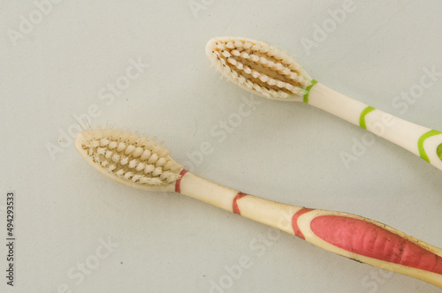 two red and green toothbrushes that have been used 