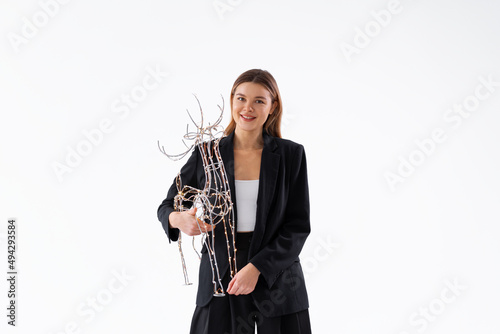 Young business woman holding illuminated Christmas deer decor dressed black suit isolated on white background