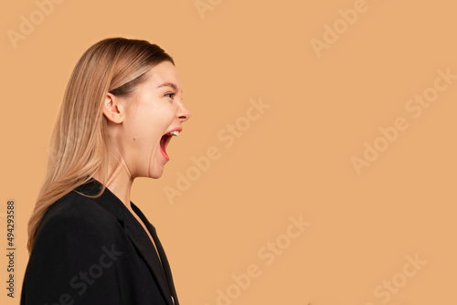 Young business woman screaming loud side view isolated on color background. Caucasian female business person aggressive yelling. Business woman shouting side photo