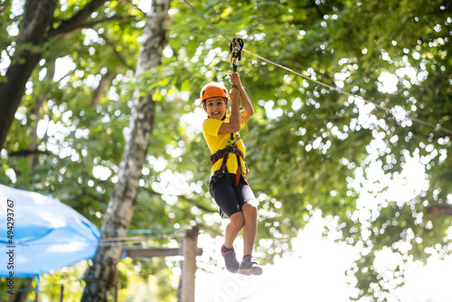 Adorable little girl enjoying her time in climbing adventure park on warm and sunny summer day