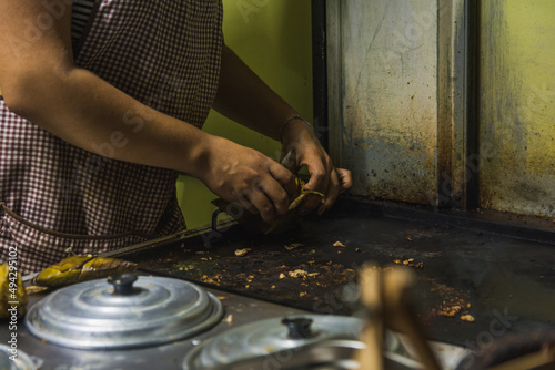 Mexican taquera woman prepares meat and chorizo tacos on the comal at her street stall.