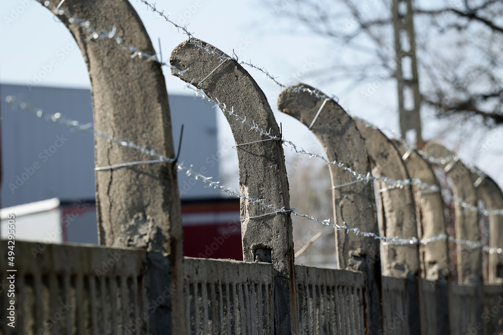 Betonowe ogrodzenie z drutu kolczastego w około obozu imigrantów. - obrazy, fototapety, plakaty 
