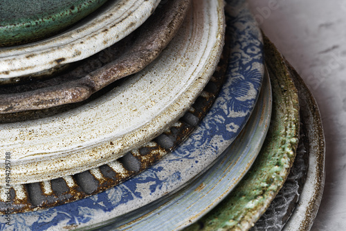 Handmade ceramic plates of various textures and sizes are stacked. Close-up, selective focus. Handmade pottery.. photo