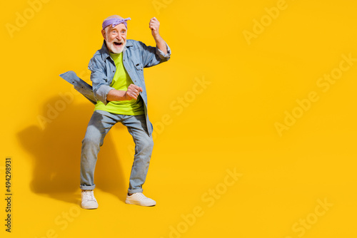 Photo of charming attractive retired man wear jeans shirt dancing empty space isolated yellow color background