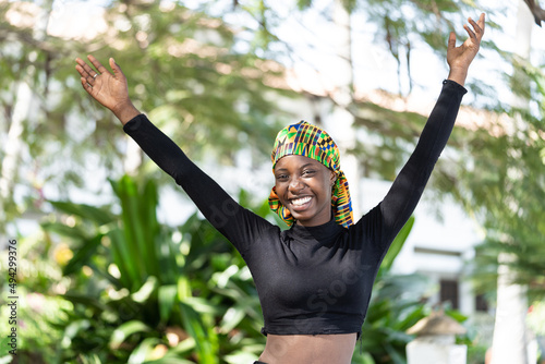 Quadro em tela Overjoyed gorgeous African girl, raising her arms up as a sign of victory, success and woman power