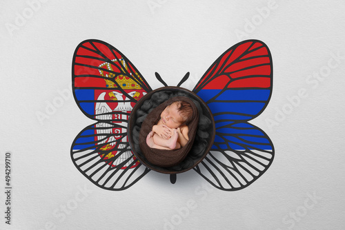 Tiny baby portrait with wings in color of national flag. Newborn photography concept. Serbia