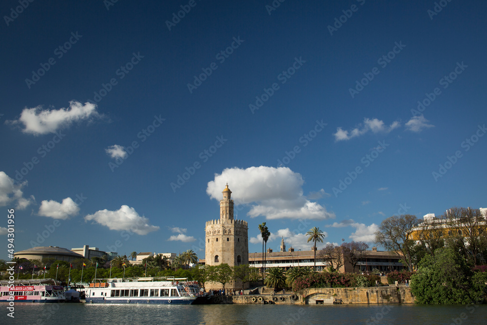 The Guadalquivir River with tourist cruises and the Oro Tower at its bank, Sevilla The Guadalquivir River with tourist cruises and the Oro Tower at its bank, Sevilla