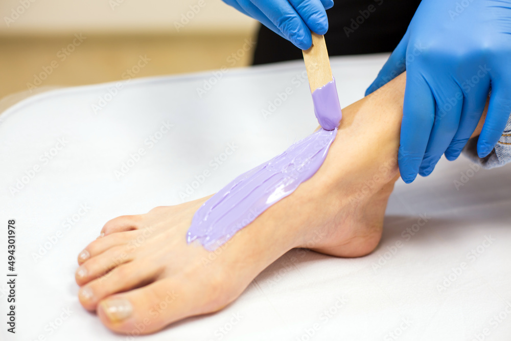 Professional sugarist is spreading sugar wax on client's leg close up Professional sugarist is spreading sugar wax on client's leg close up