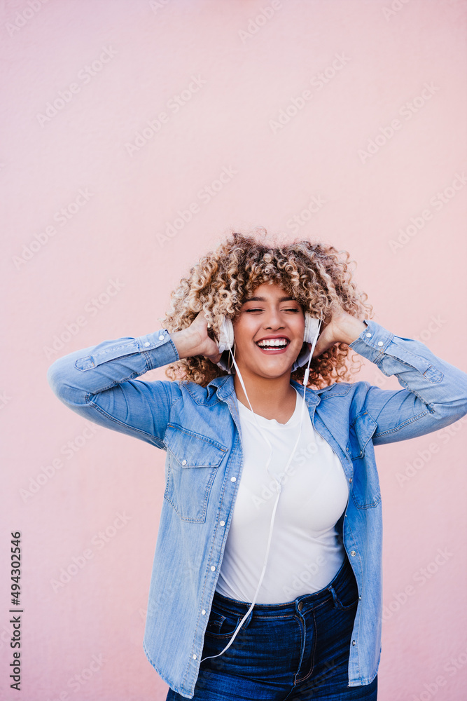 happy curvy hispanic woman with afro hair in city using mobile phone and headset. Body positivity happy curvy hispanic woman with afro hair in city using mobile phone and headset. Body positivity