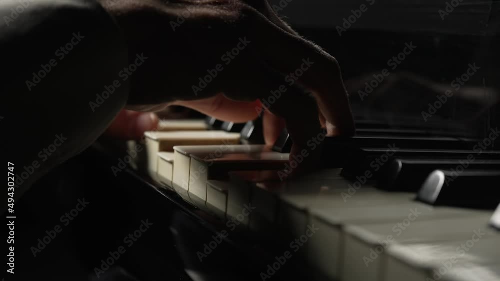 Male pianist plays fast music on piano in dark. Musician touches white and black keys of string instrument with his fingers creating musical melody. Male hands close up. Slow motion ready at 59.94fps.