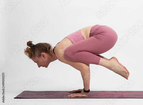 woman doing yoga on a white background kakasana photo