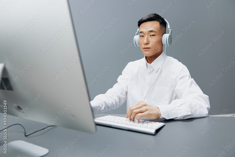 Asian man in headphones at the table in front of the computer Lifestyle work Asian man in headphones at the table in front of the computer Lifestyle work