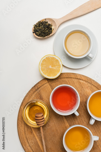 Top view of cups of tea near honey and lemon on white background.