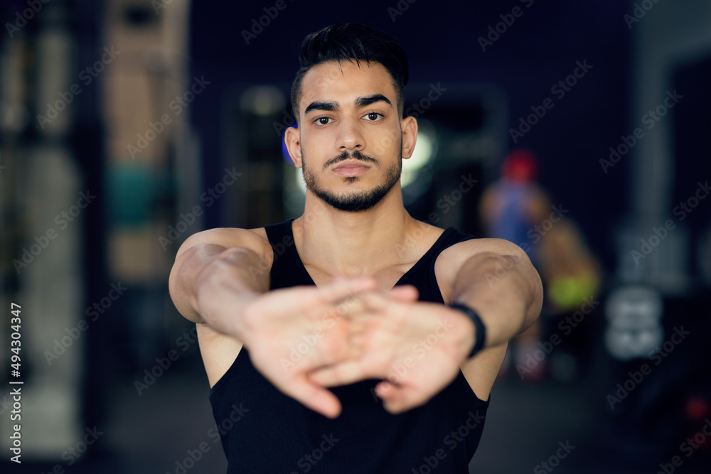 Fototapeta premium Portrait Of Sporty Young Arab Man Stretching Arms At Camera